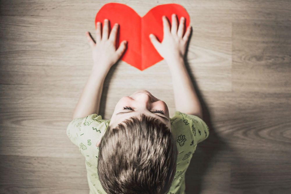 an autistic child holding a red paper heart