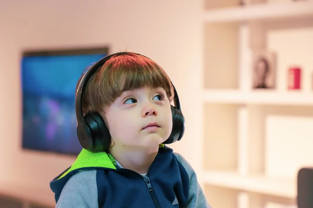 a boy wearing a hoodie listening to music with headphones