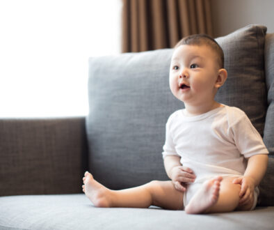 Infant sitting on a sofa showing early developmental behaviors and expressions, a topic covered in recognizing the early signs of autism in infants