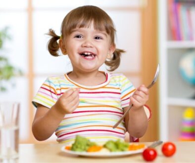 Happy child with autism eating a nutritious meal with vegetables, part of a healthy diet recommended for autism support.