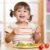 Happy child with autism eating a nutritious meal with vegetables, part of a healthy diet recommended for autism support.