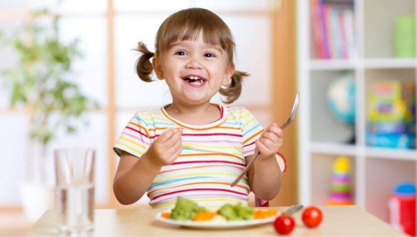 Happy child with autism eating a nutritious meal with vegetables, part of a healthy diet recommended for autism support.