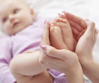 Mother holding infant’s feet, symbolizing early signs of autism in babies