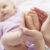 Mother holding infant’s feet, symbolizing early signs of autism in babies