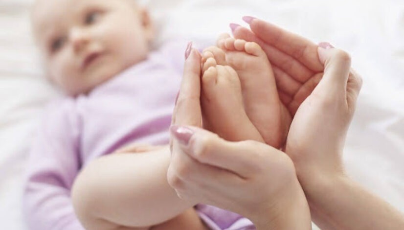 Mother holding infant’s feet, symbolizing early signs of autism in babies