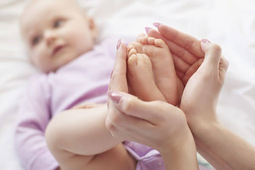 Mother holding infant’s feet, symbolizing early signs of autism in babies